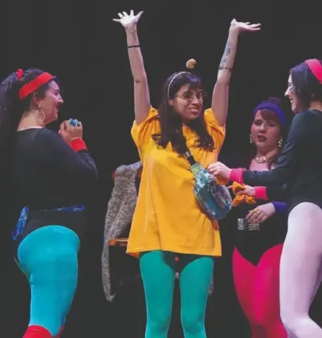 Grupo en el Teatro Colsubsidio con vestuario colorido y gestos expresivos.