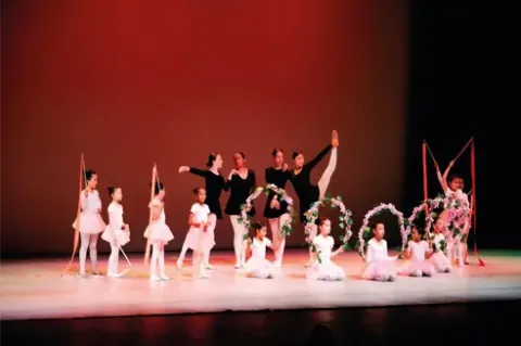 Bailarinas de ballet en el Teatro Colsubsidio: niñas con cintas y aros, jóvenes con vestuario negro.