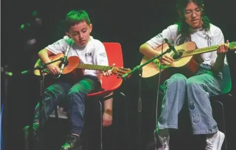 Dúo en el Teatro Colsubsidio interpreta guitarras en escena, mostrando colaboración y aprendizaje musical.