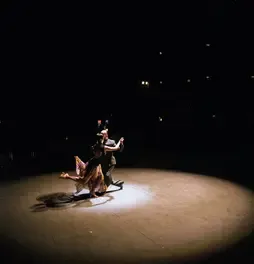 Pareja bailando tango bajo un reflector de luz en el Teatro Colsubsidio.