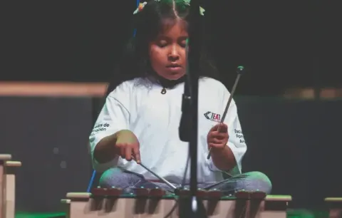Niña en el Teatro Colsubsidio interpreta xilófono con concentración.
