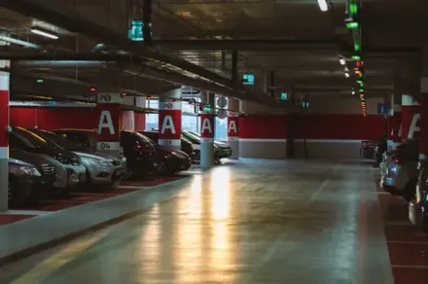 Estacionamiento subterráneo de Teatro Colsubsidio con coches aparcados y pilares numerados "A".