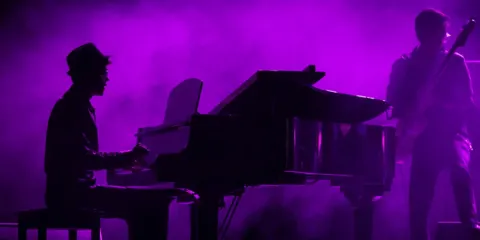 Silueta de pianista tocando un piano de cola en el Teatro Colsubsidio.