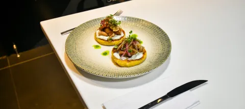 Plato gourmet del Café de las Letras, con base dorada, crema, carne, cebolla y microgreens.