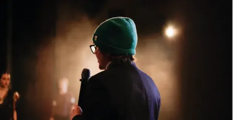Orador de espaldas con gorro verde y micrófono en el Teatro Colsubsidio.