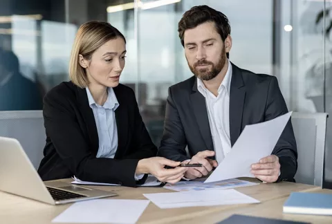 Un asesor y una empresaria analizando deducciones y beneficios tributarios estratégicos.