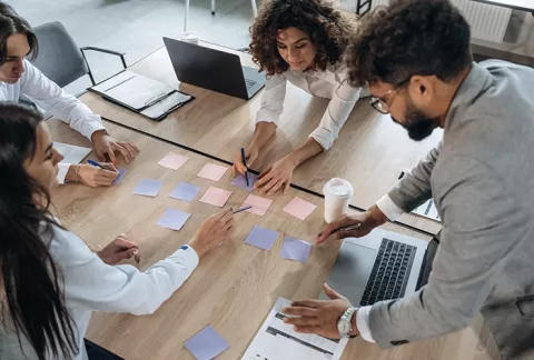 Equipo de trabajo colaborando alrededor de una mesa con notas, curso Innovación Colsubsidio.
