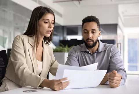 Dos personas revisando la normativa fiscal para aplicar la eficiencia tributaria en la empresa.