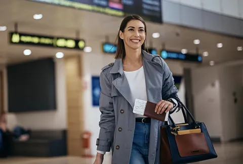 Persona con maleta de viaje en un aeropuerto, beneficio Tiquetes Incluidos.