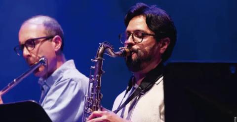 Dos músicos interpretando saxofón y flauta traversa en una presentación de jazz en vivo.