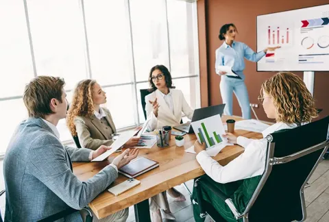Equipo directivo analiza gráficas de gestión durante una reunión de trabajo
