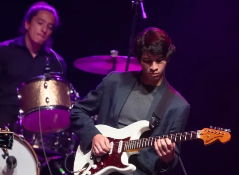 Joven tocando la guitarra en un escenario del Teatro Colsubsidio.