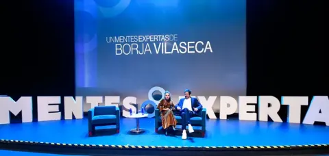 Dos expertos en escenario de un curso "Mentes Expertas de Borja Vilaseca" con pantalla y letras 3D.