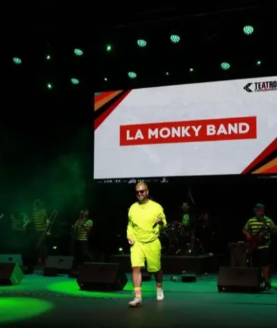 Vocalista en conjunto neón cantando en vivo junto a su agrupación en el escenario.
