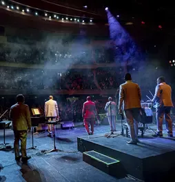 Integrantes de la Orquesta Aragón interpretando sus instrumentos de espaldas ante el público.