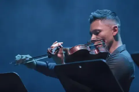 Violinista concentrado interpretando una pieza musical en el escenario.