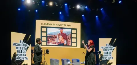 Ponentes en escenario de curso con pantallas, una mostrando "El Bueno, El Malo y El Feo".