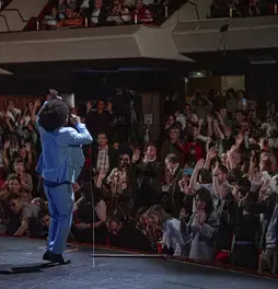 Cantante de la Orquesta Aragón con traje azul animando al público en el escenario.