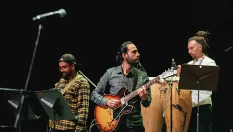 Guitarristas en concierto interpretando sus instrumentos frente al público.