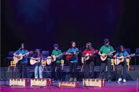 Agrupación infantil y juvenil tocando guitarras y tiples en una presentación musical.