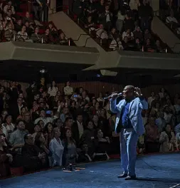 Integrante de la Orquesta Aragón cantando frente a un auditorio lleno de espectadores.
