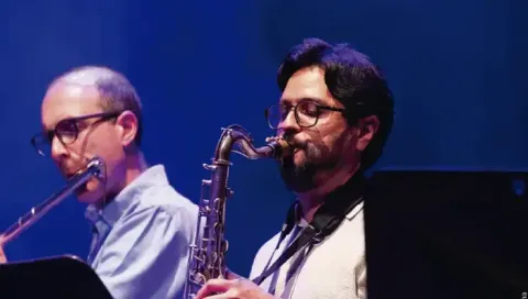 Saxofonista y flautista tocando concentrados durante una presentación de jazz.